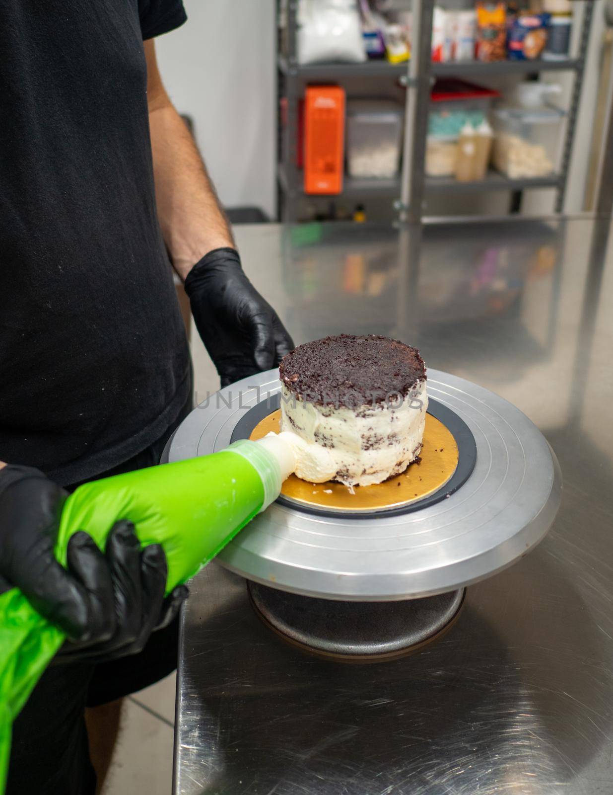 decorator applying buttercream to frosted cake with bag full of cream