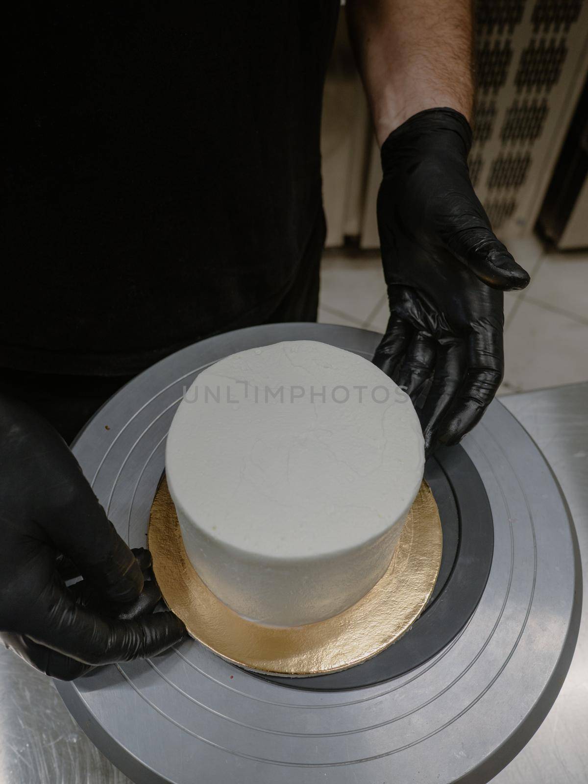 Decorator using spatula and scraper to smooth buttercream on a frosted cake