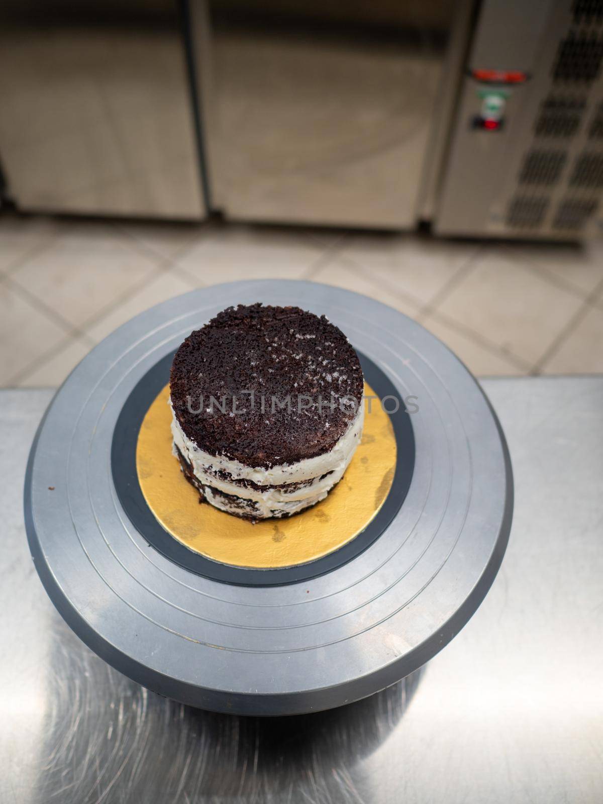 Decorator using spatula and scraper to smooth buttercream on a frosted cake