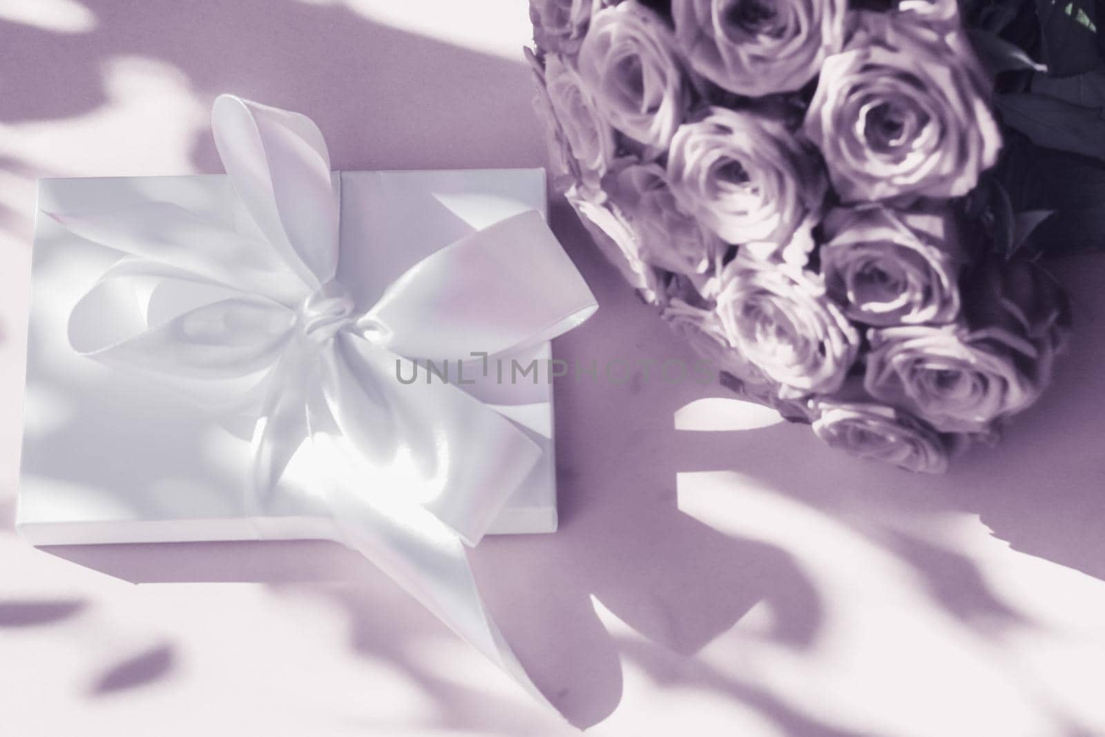 Luxury holiday silk gift box and bouquet of roses on purple background, romantic surprise and flowers as birthday or Valentines Day present by Anneleven