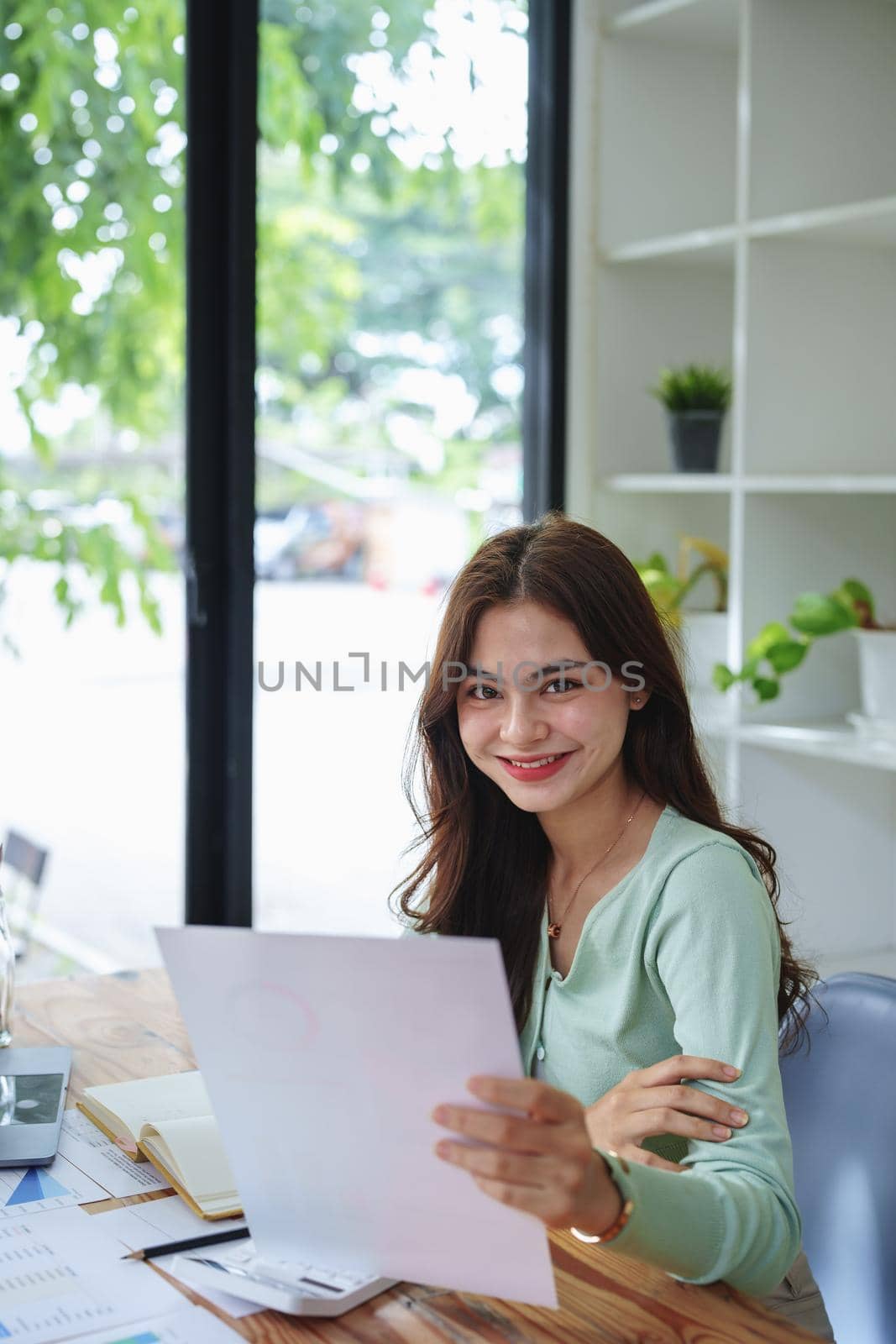 A businesswoman, an accountant, half girl,showing a smiling face while working on financial documents and using computers to check taxes and budgets for internal company spending.