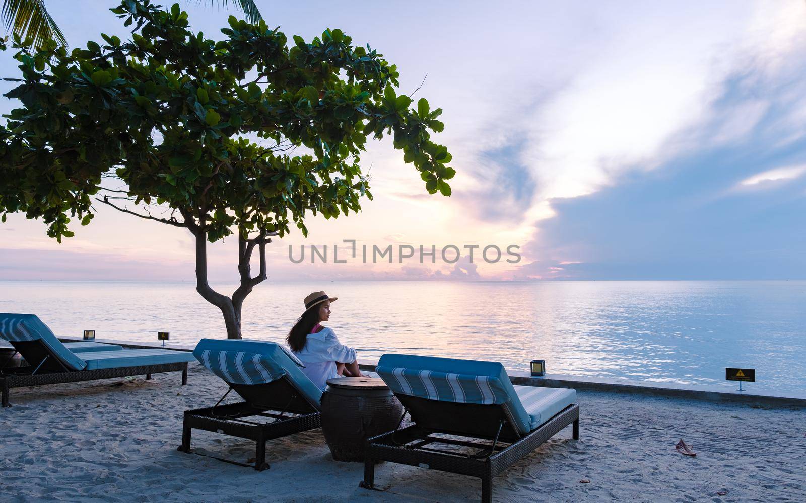 Asian women on a Tropical beach with palm trees and beach chairs on a white beach in Hua Hin Thailand. palm trees and beach chairs