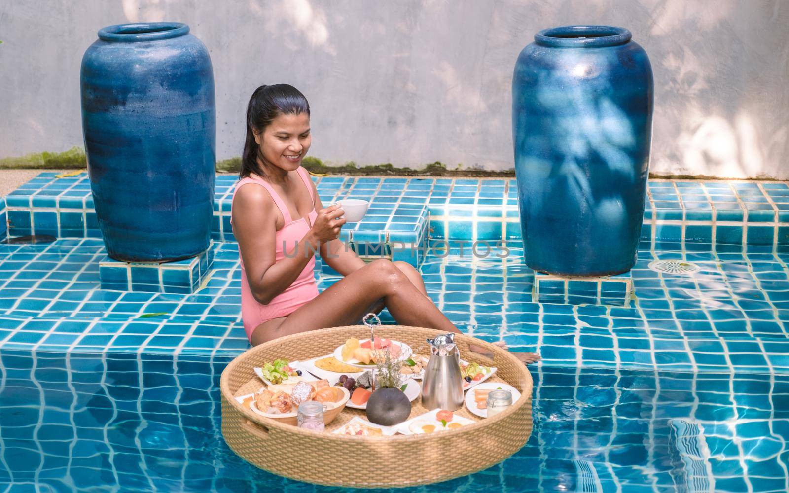 women having breakfast in swimming pool , Asian women having floating breakfast by fokkebok