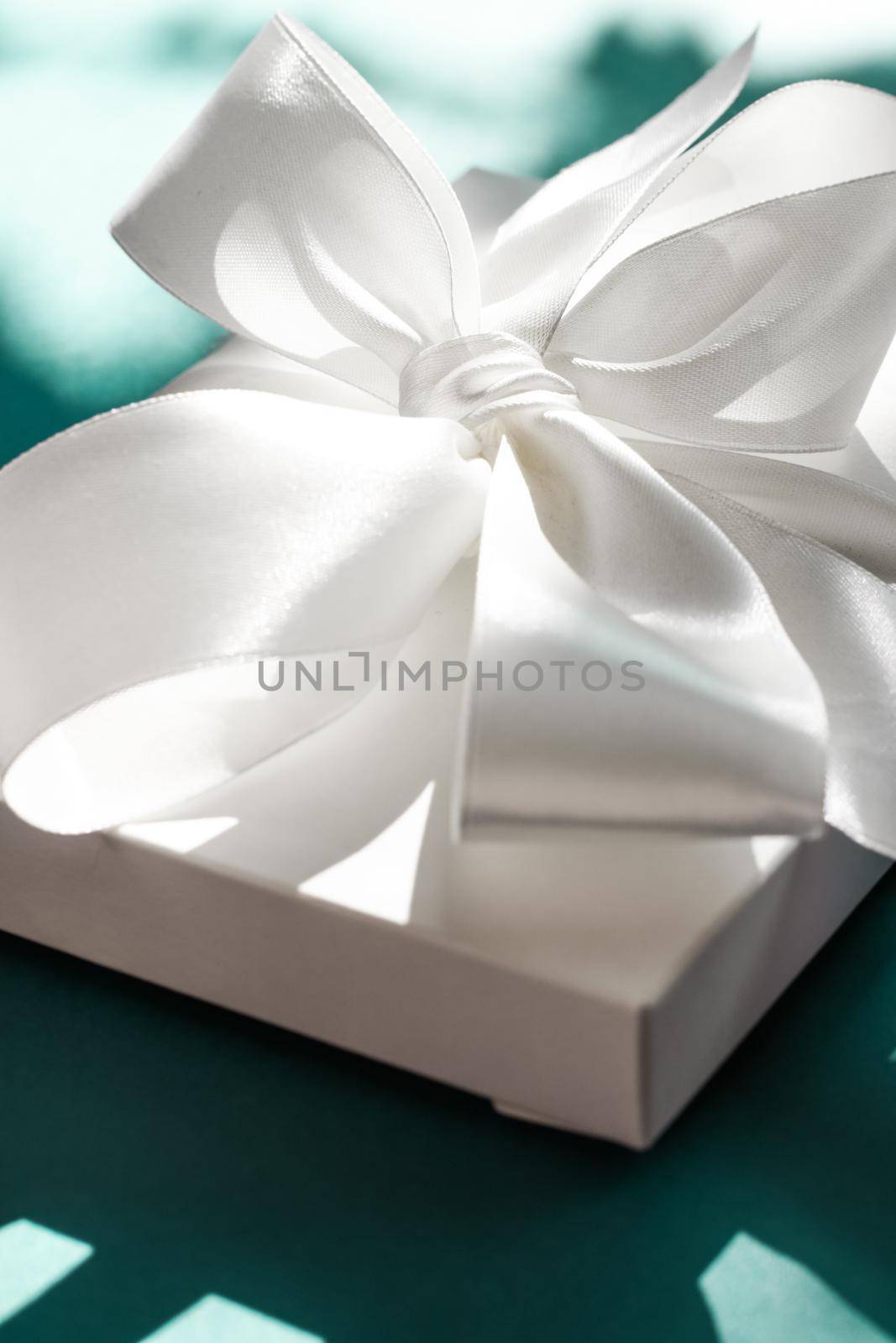 Luxury holiday white gift box with silk ribbon and bow on emerald green background, luxe wedding or birthday present by Anneleven