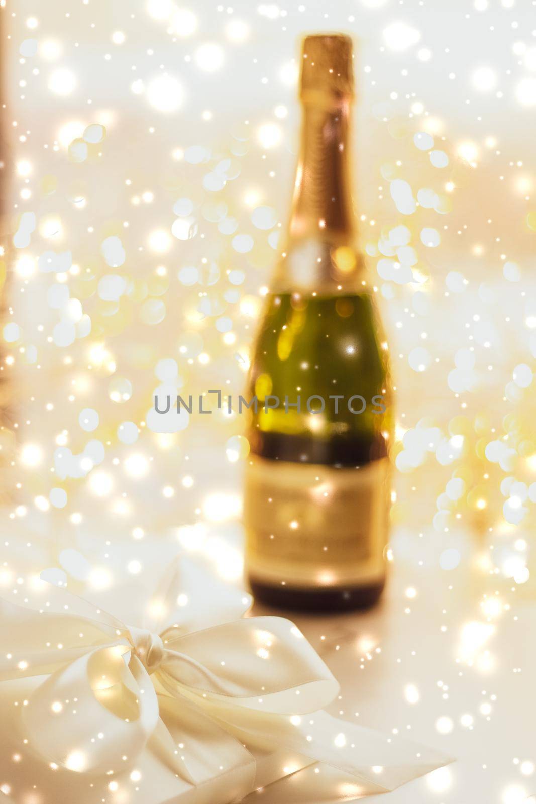 New Years Eve holiday champagne bottle and a gift box and shiny snow on marble background by Anneleven