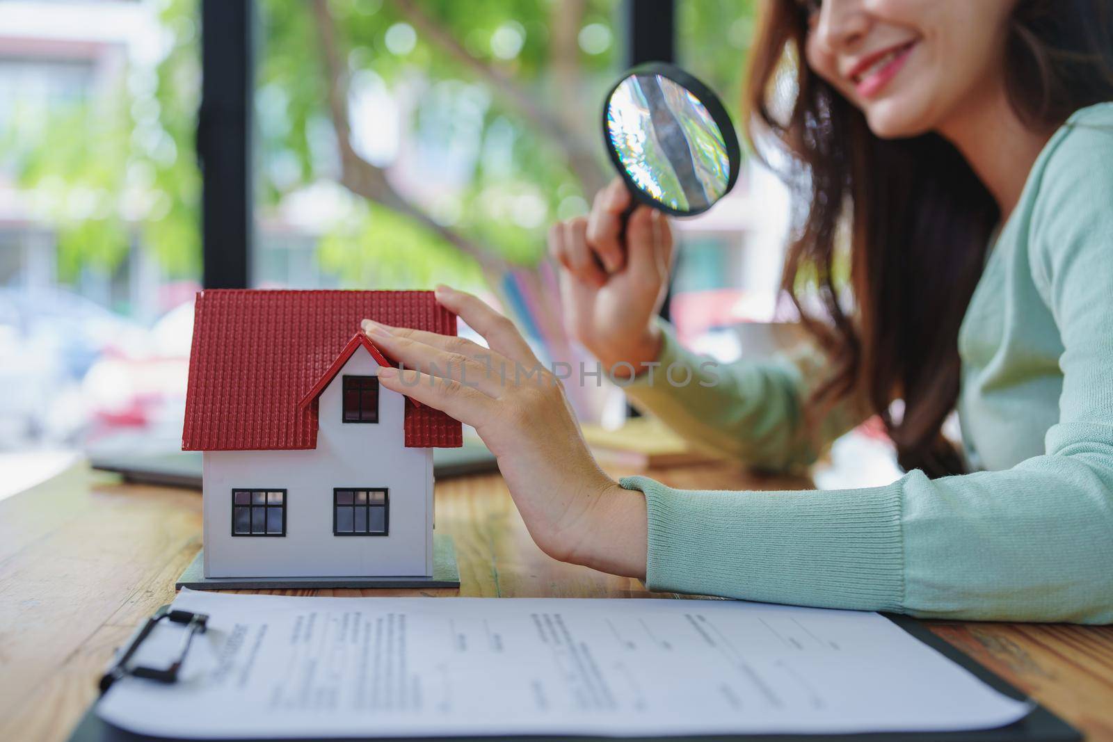 customer holding a magnifying glass to look at a house model inspection by Manastrong