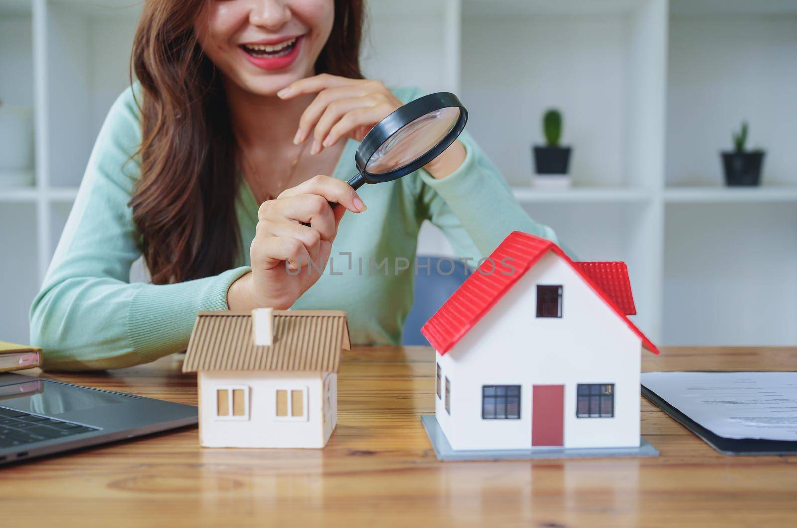 Customer holding a magnifying glass to select a house model, residential inspection concept by Manastrong