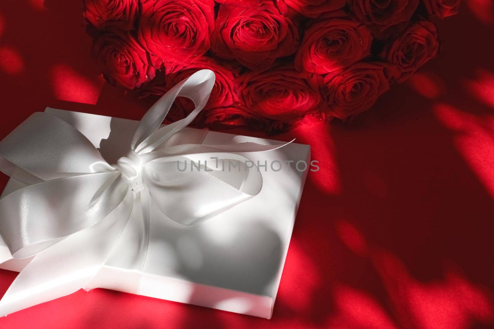 Happy holidays, luxe shopping and love gifts concept - Luxury holiday silk gift box and bouquet of roses on red background, romantic surprise and flowers as birthday or Valentines Day present