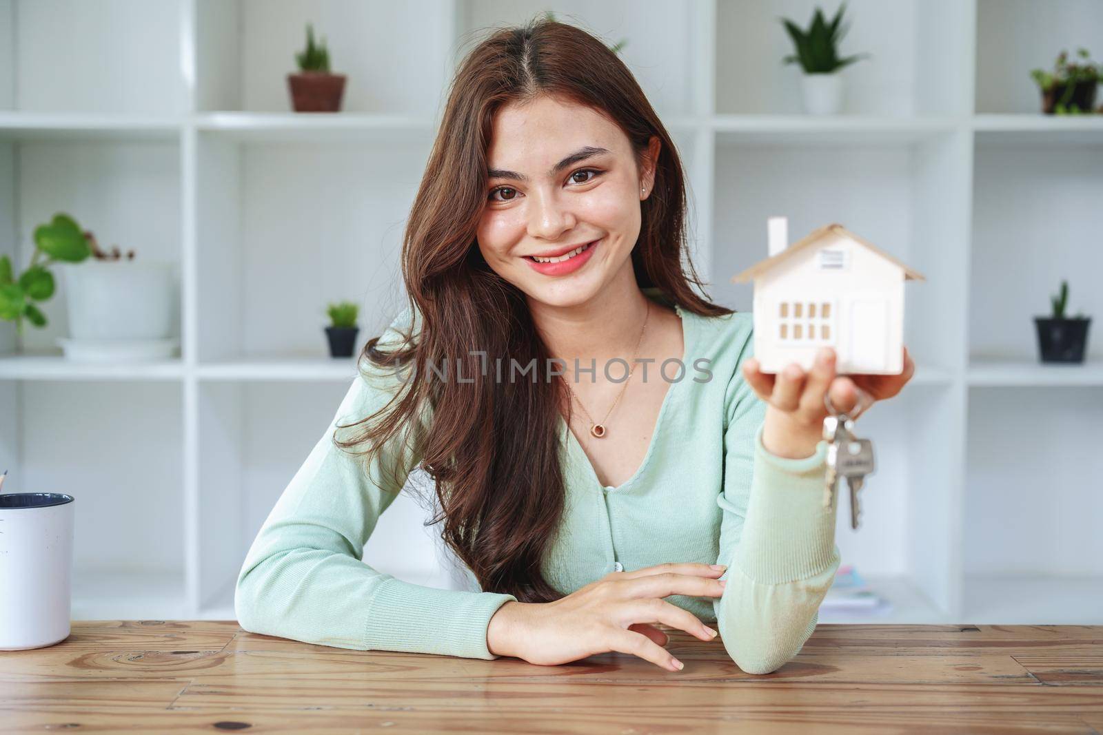 The customer holds the house model and keys after agreeing to invest in the housing purchase.