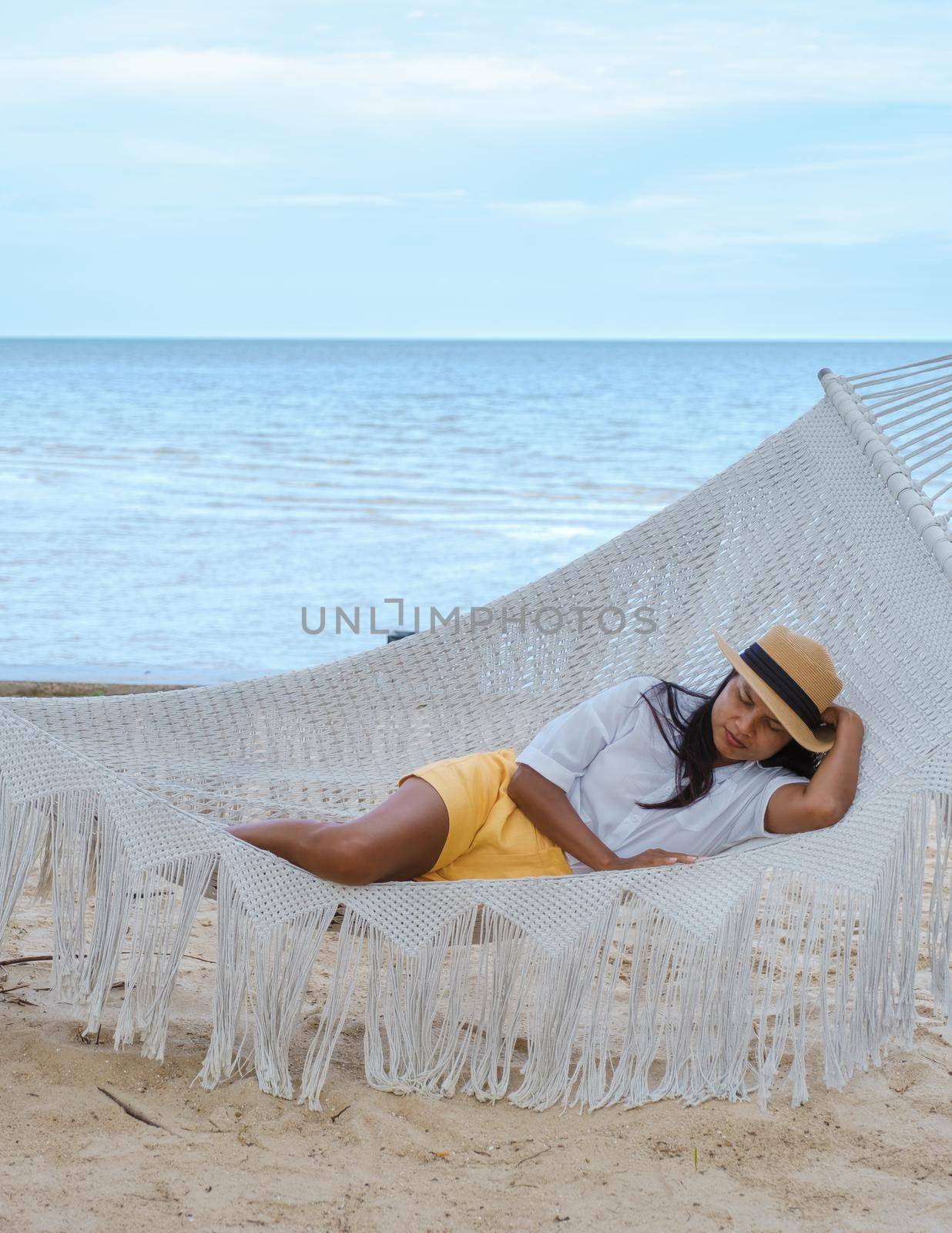 women sleeping in hammock on a beach in Thailand, Asian women taking a nap in afternoon by fokkebok