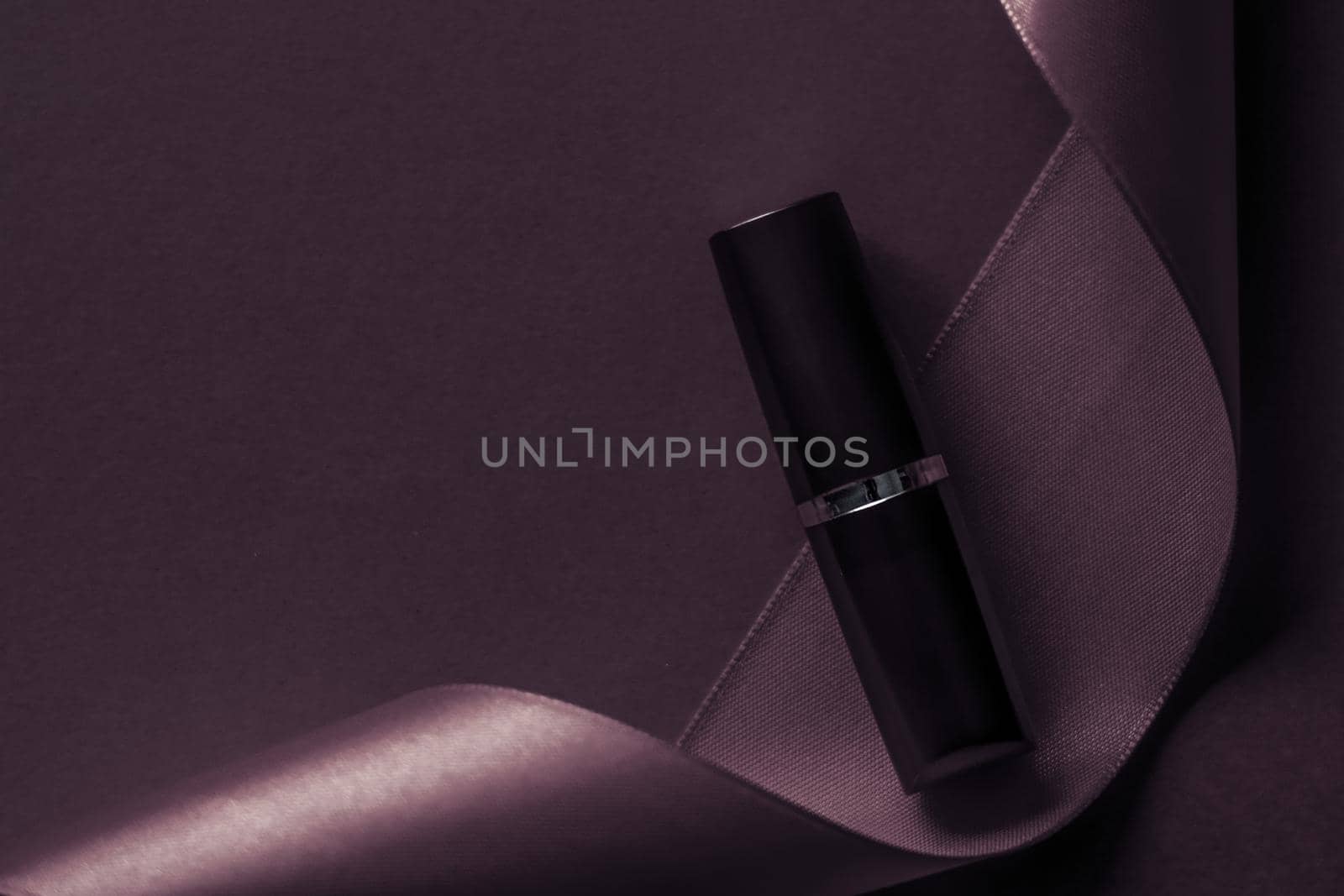 Cosmetic branding, glamour lip gloss and shopping sale concept - Luxury lipstick and silk ribbon on dark purple holiday background, make-up and cosmetics flatlay for beauty brand product design
