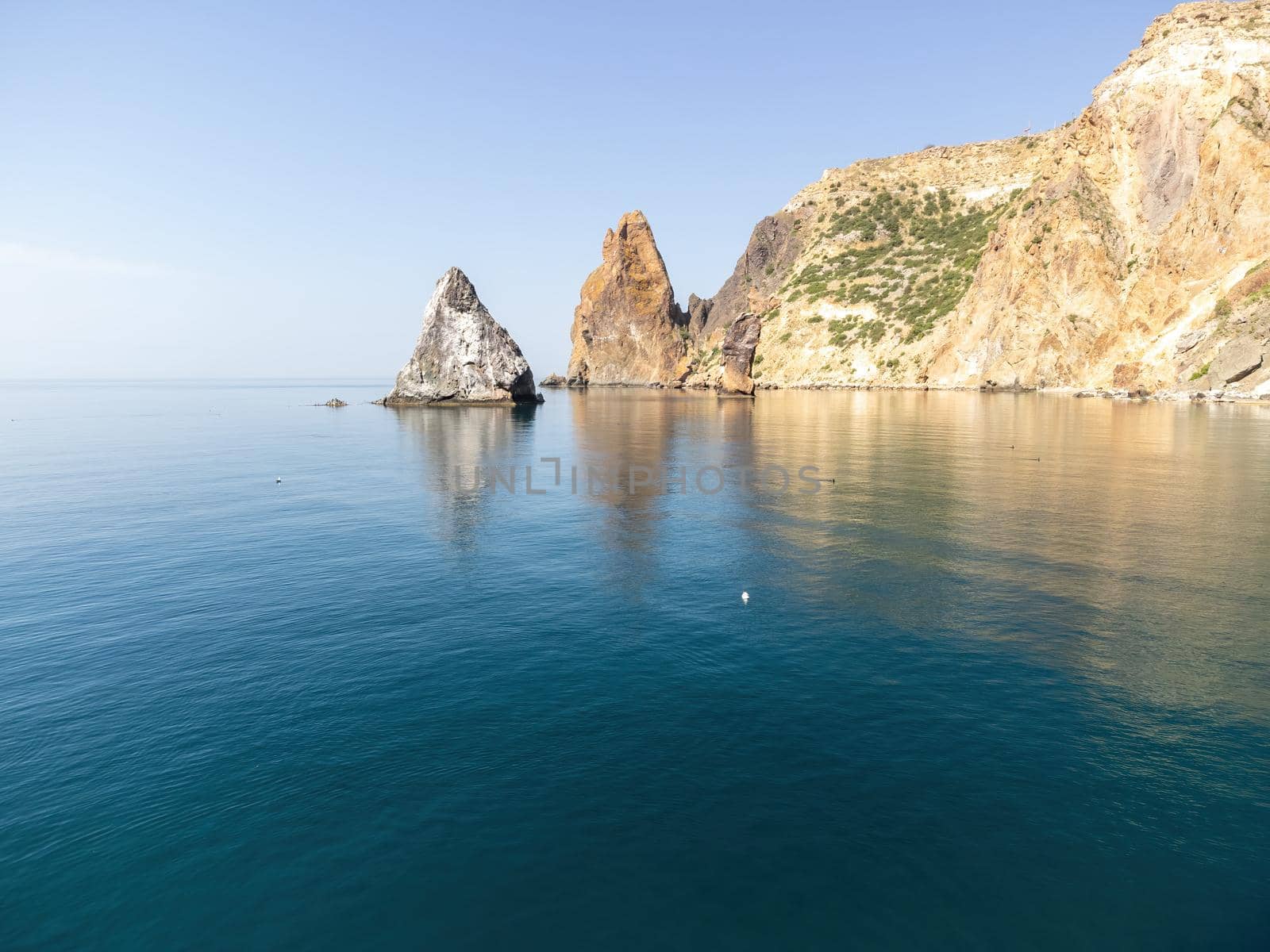 Sea landscape with rocky coastline on sunset time with cloudy sky. Yachts in the Sea on a background of rocky shores. The concept of perfect place for summer travel and rest.