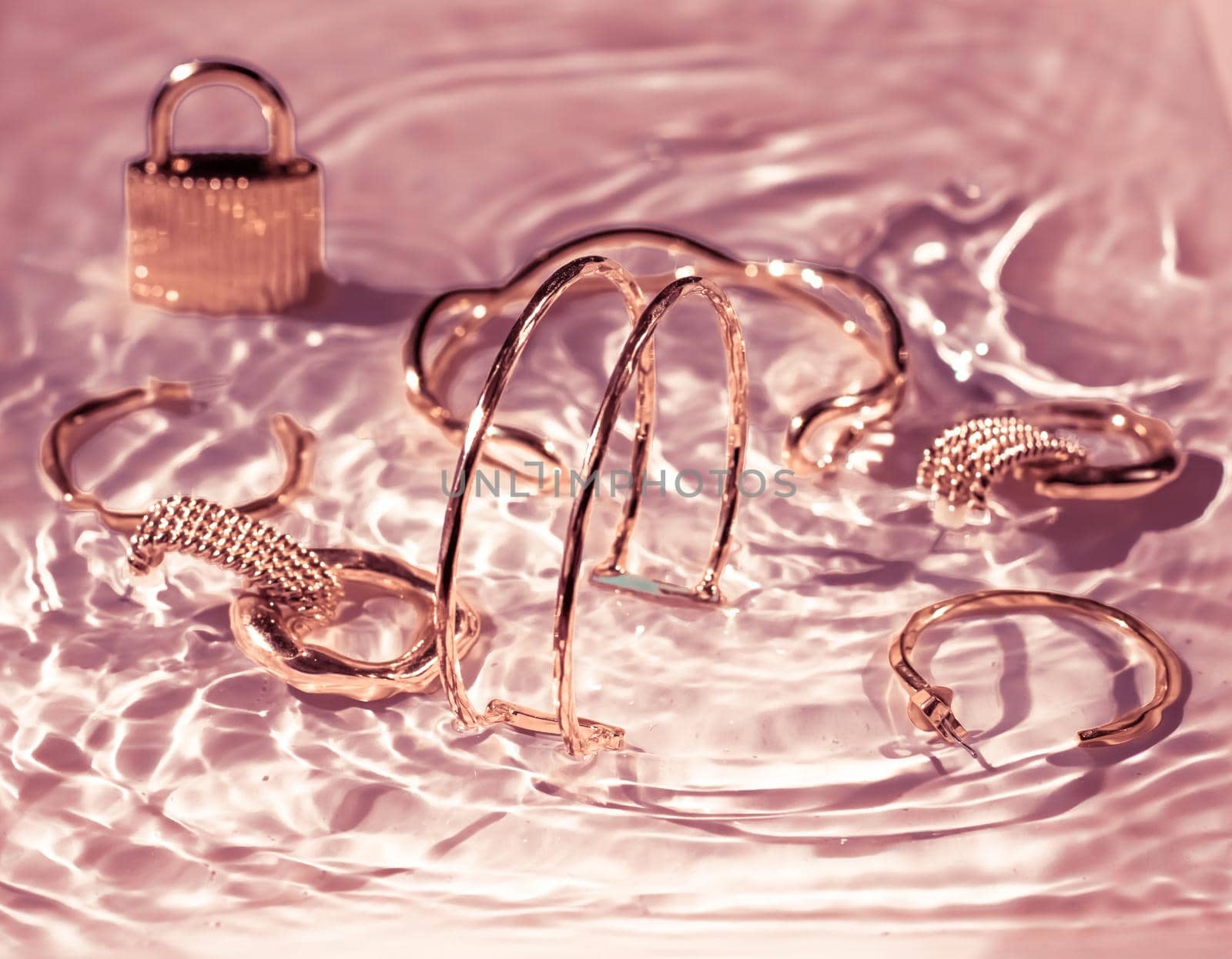 Rose gold bracelets, earrings, rings, jewelery on pink water background, luxury glamour and holiday beauty design for jewelry brand ads by Anneleven
