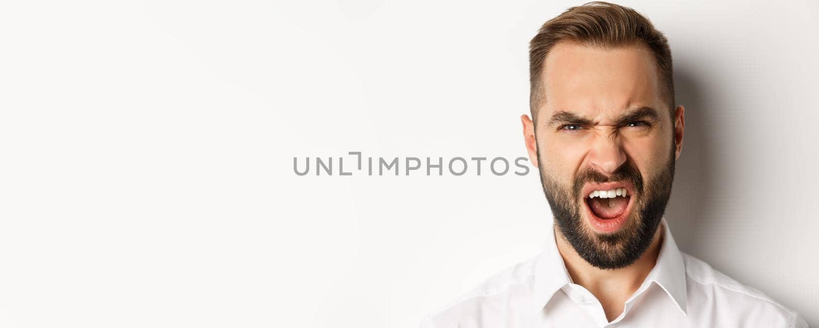 Emotions and people concept. Close-up of shocked bearded man reacting to something disappointed, complaining and grimacing, white background.