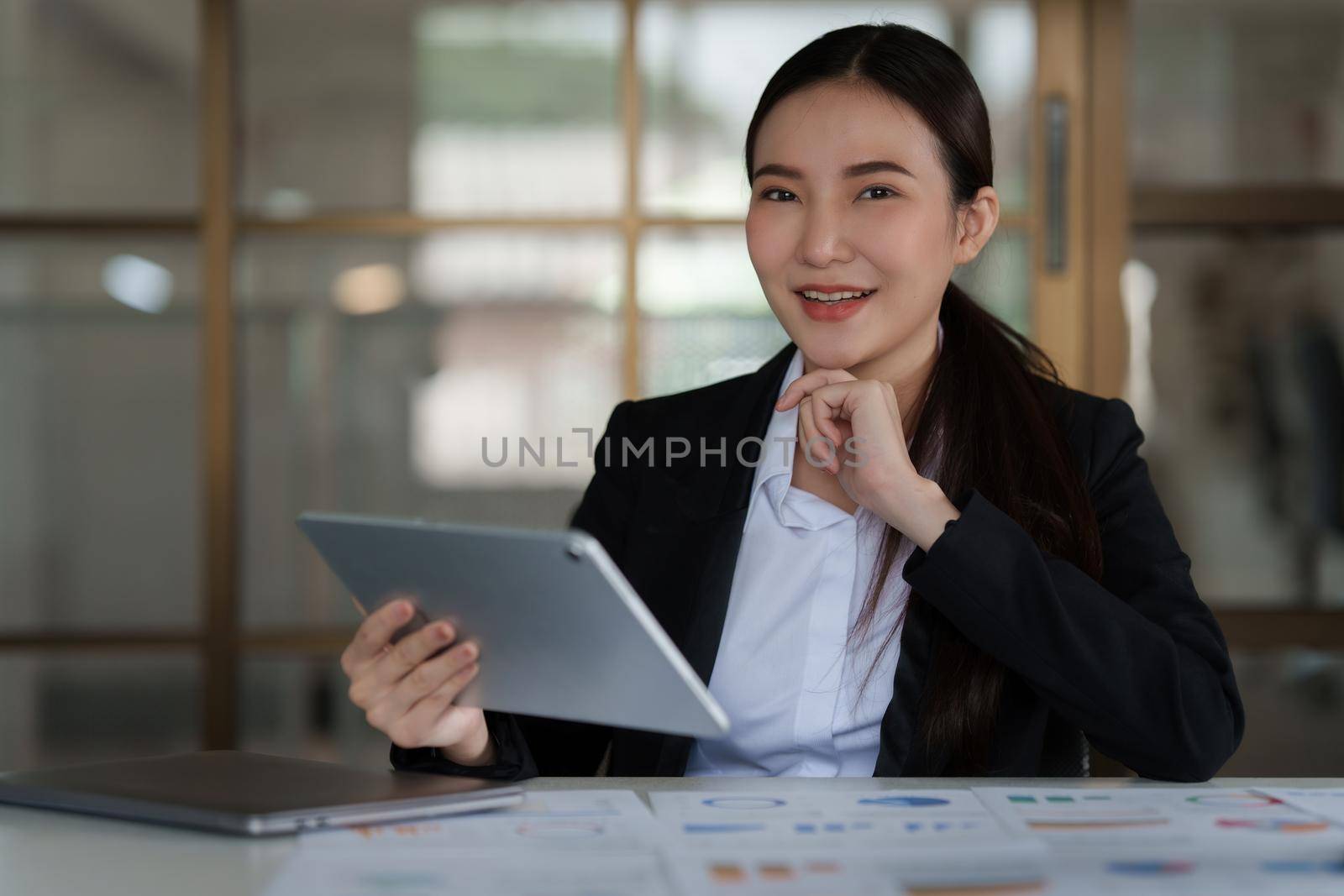 Asian Business woman working to analyze technical price graph and indicator with business team talking by cell phone. account or saving money or insurance concept.