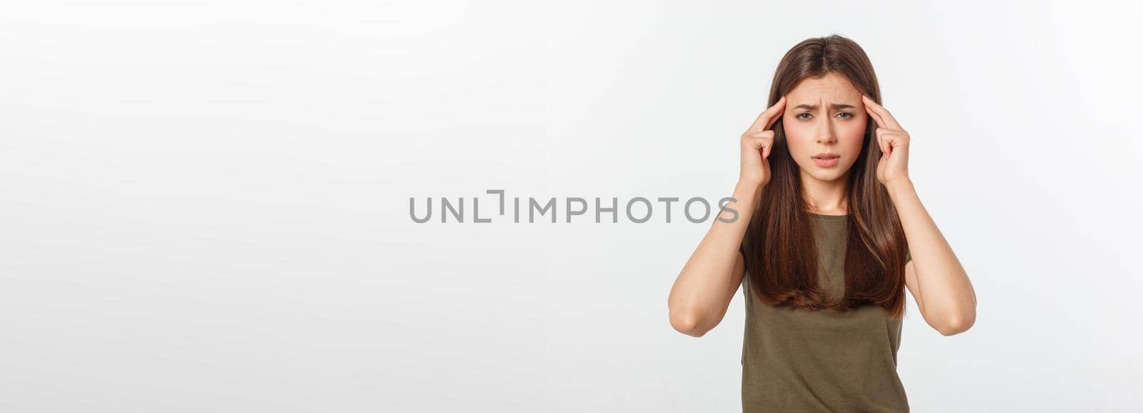 A young attractive woman suffering from illness or headache holding her head. Isolated on white.