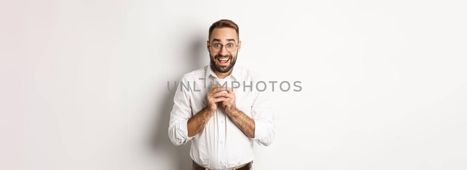 Man drinking coffee and looking excited, enjoying drink, standing over white background.