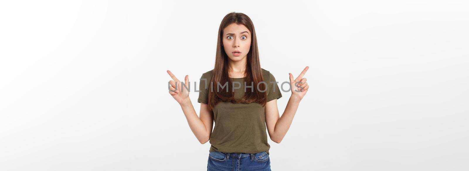Portrait happy and surprised young lady standing isolated over grey background. Looking camera pointing