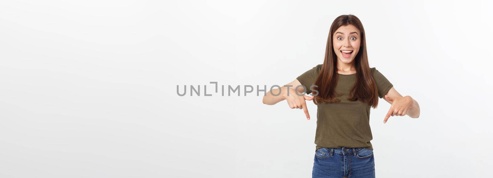 Portrait happy and surprised young lady standing isolated over grey background. Looking camera pointing