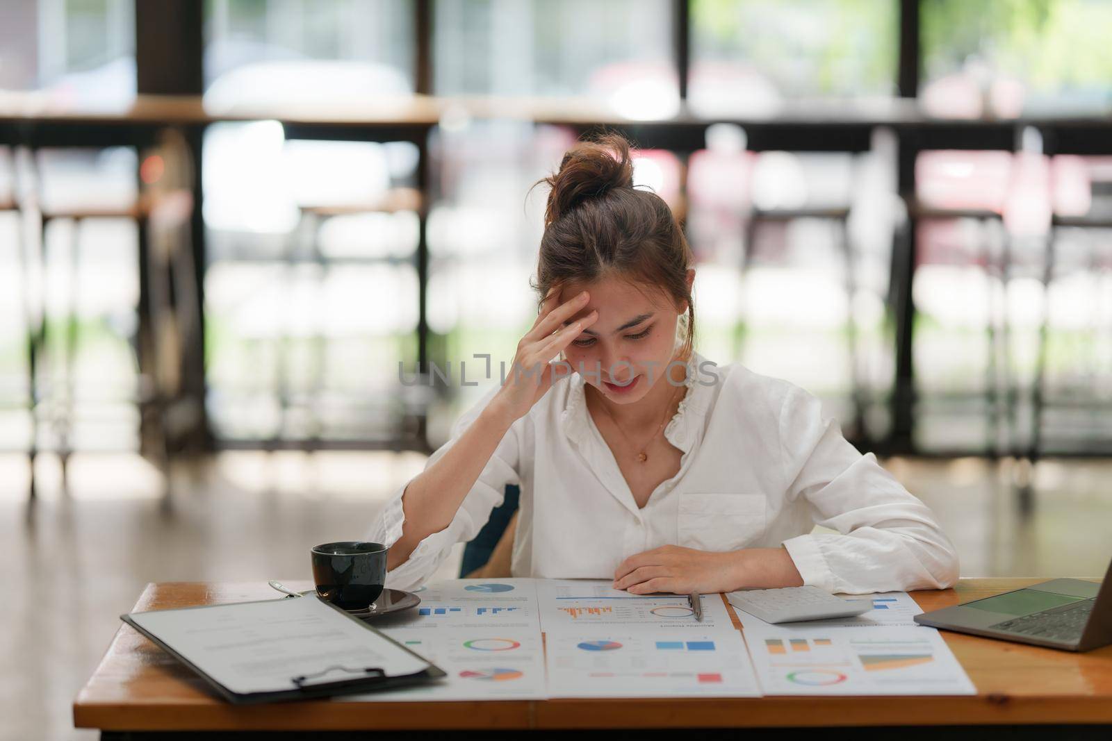 Stressed Asian business woman worry with many document on desk at office.