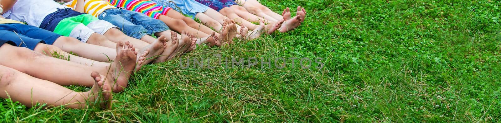 Children's feet lie on the grass. Selective focus. Kid.