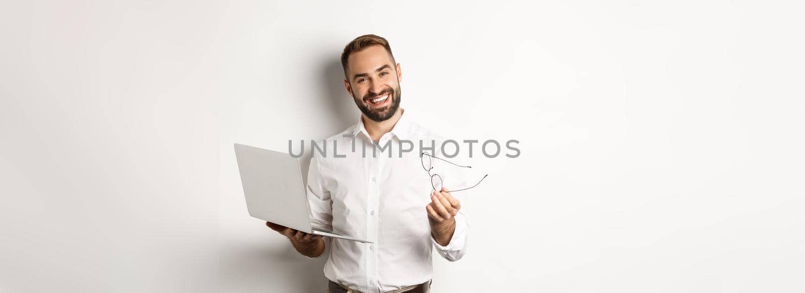 Satisfied businessman praising good job while checking laptop, standing over white background. Copy space
