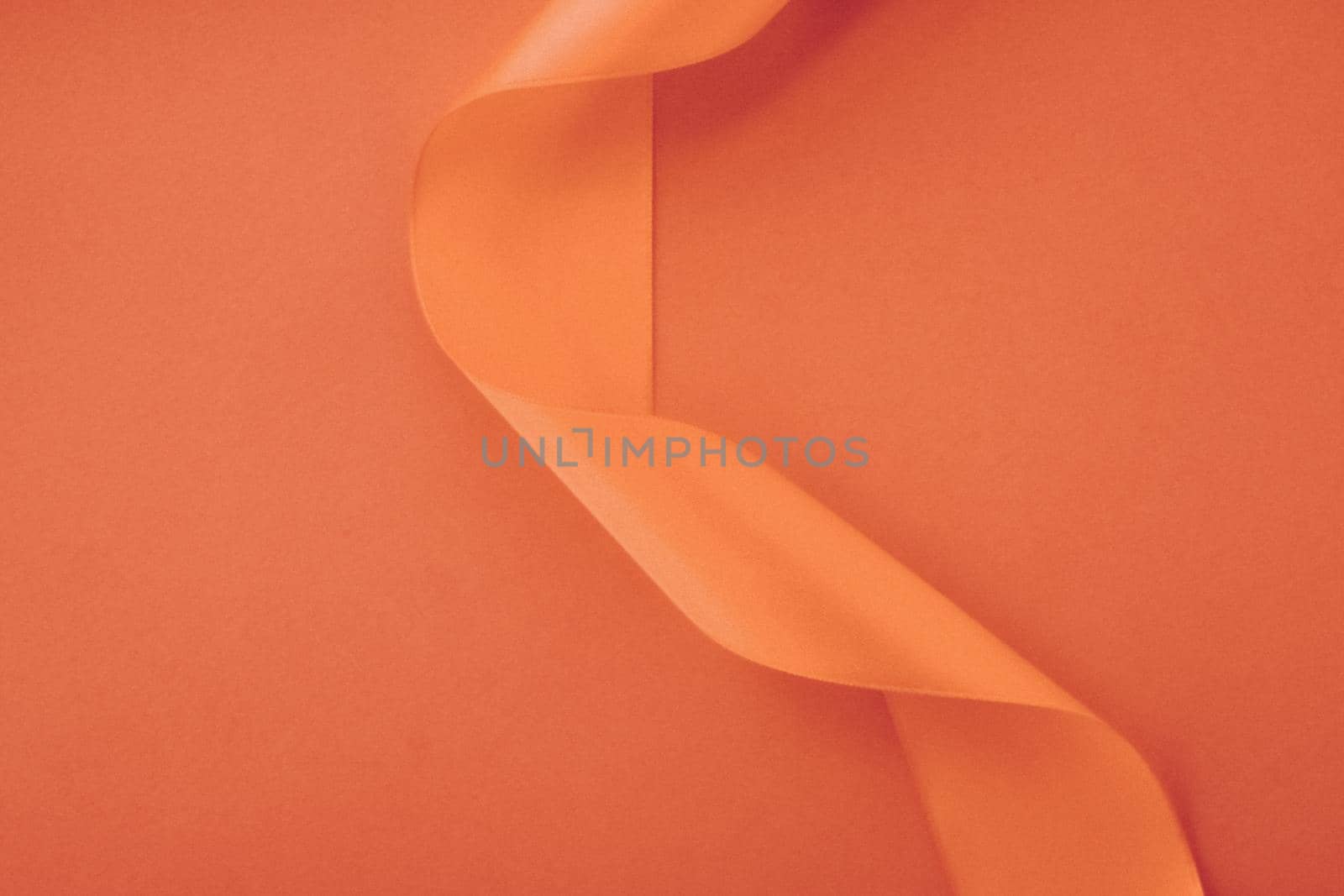 Branding, holidays and luxe brands concept - Abstract curly silk ribbon on orange background, exclusive luxury brand design for holiday sale product promotion and glamour art invitation card backdrop
