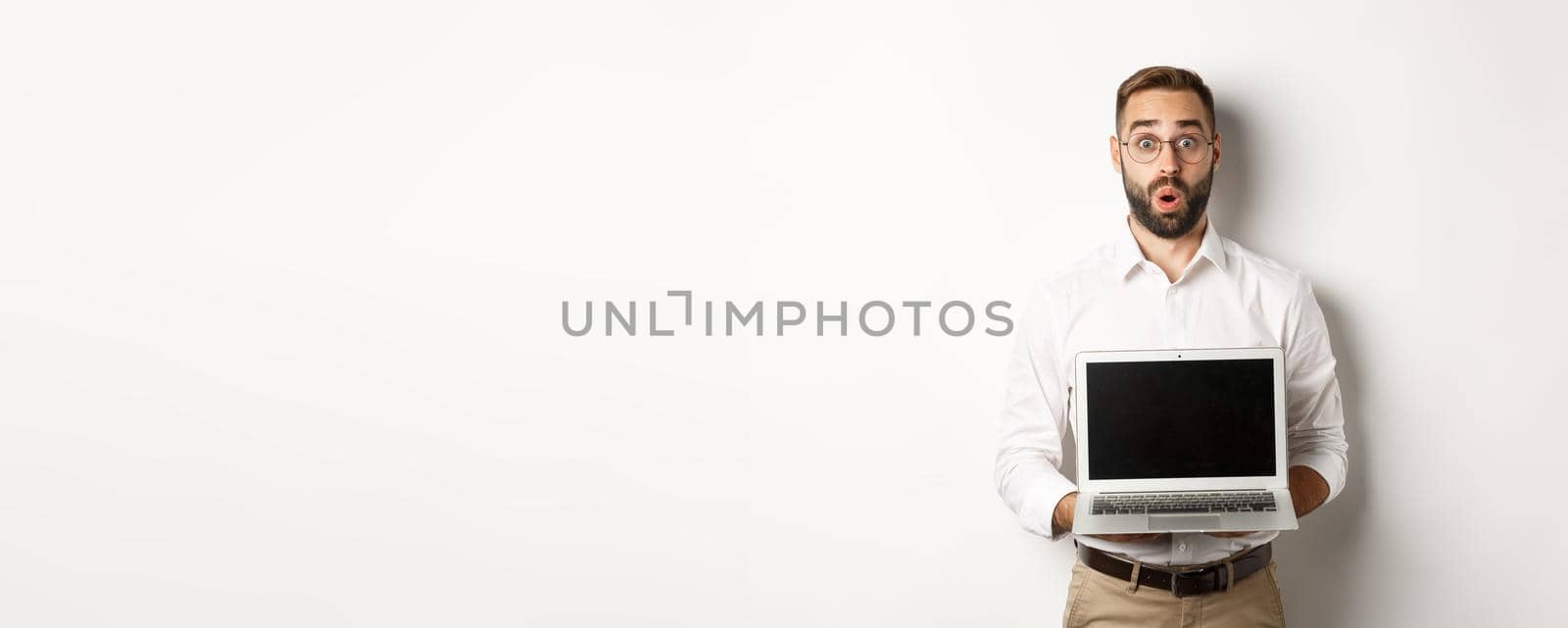 Excited businessman showing something on laptop screen, standing happy over white background by Benzoix