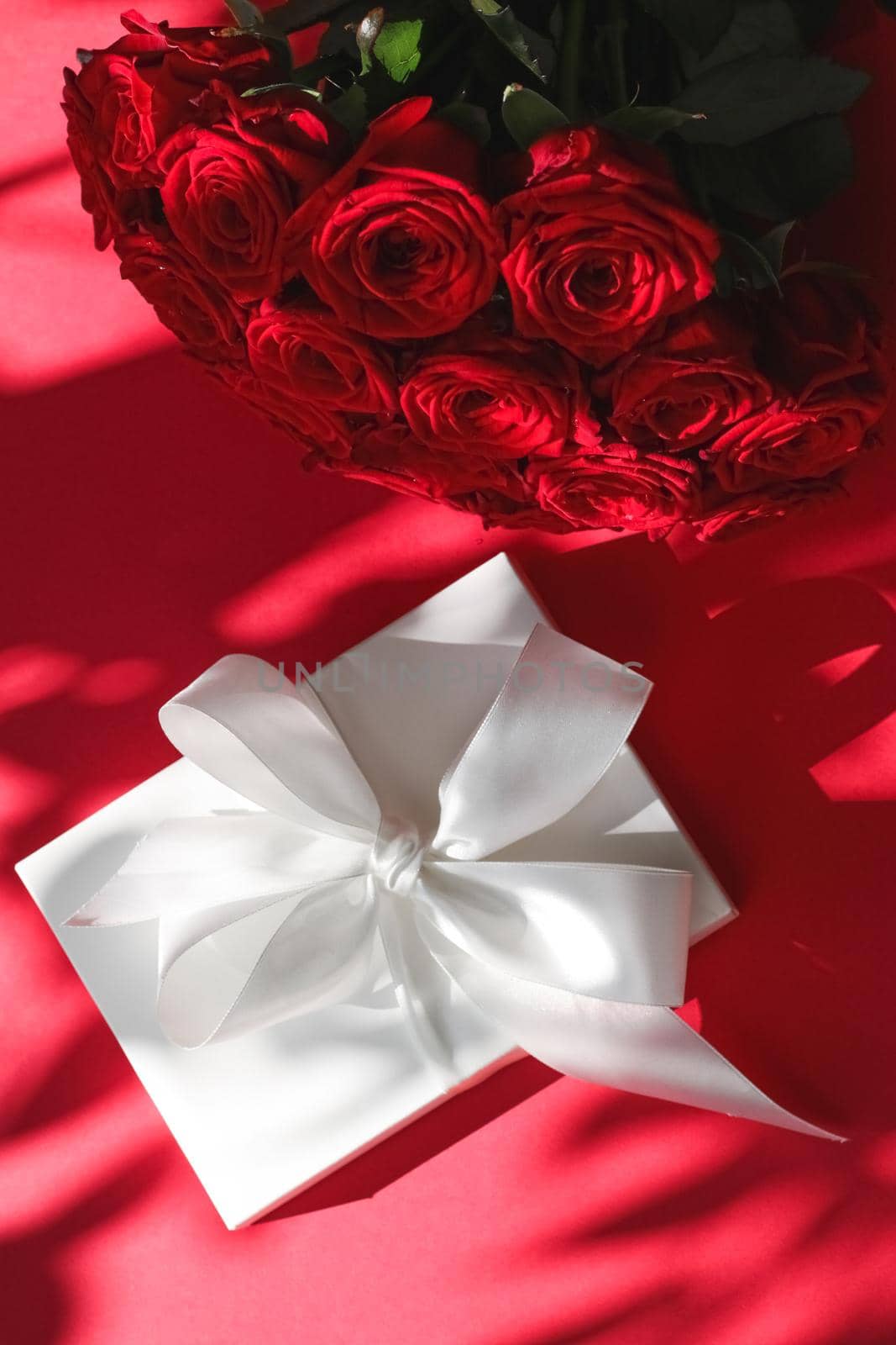 Happy holidays, luxe shopping and love gifts concept - Luxury holiday silk gift box and bouquet of roses on red background, romantic surprise and flowers as birthday or Valentines Day present