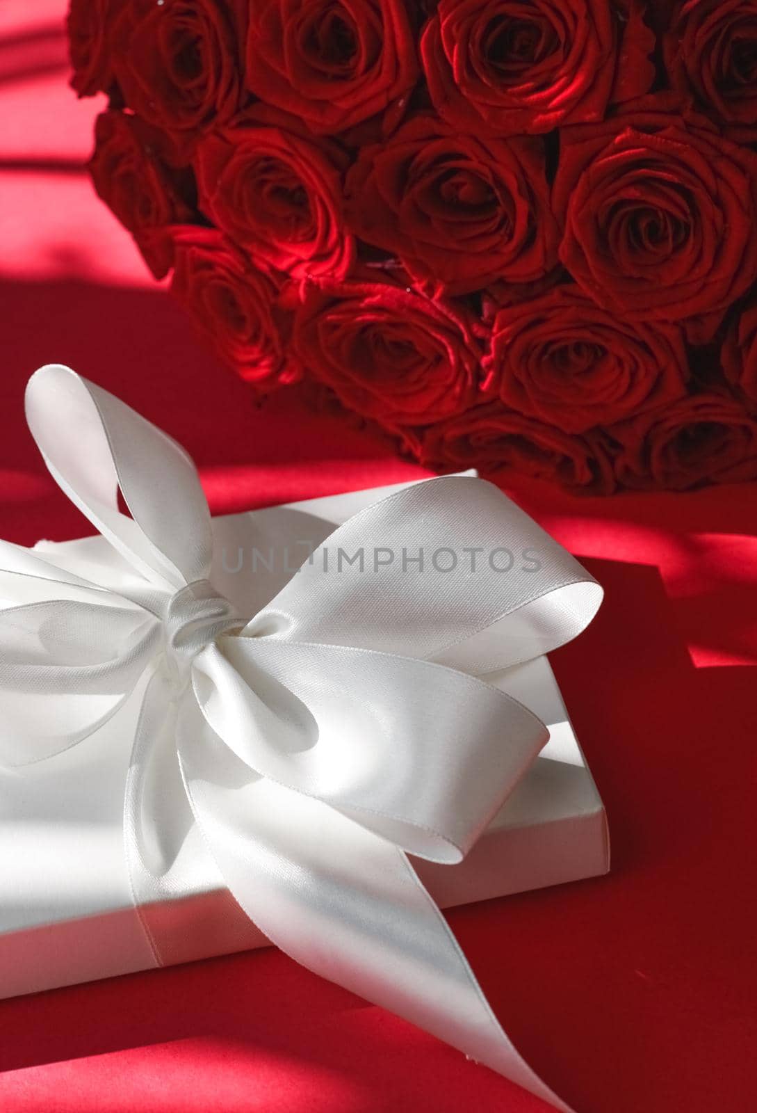 Luxury holiday silk gift box and bouquet of roses on red background, romantic surprise and flowers as birthday or Valentines Day present by Anneleven