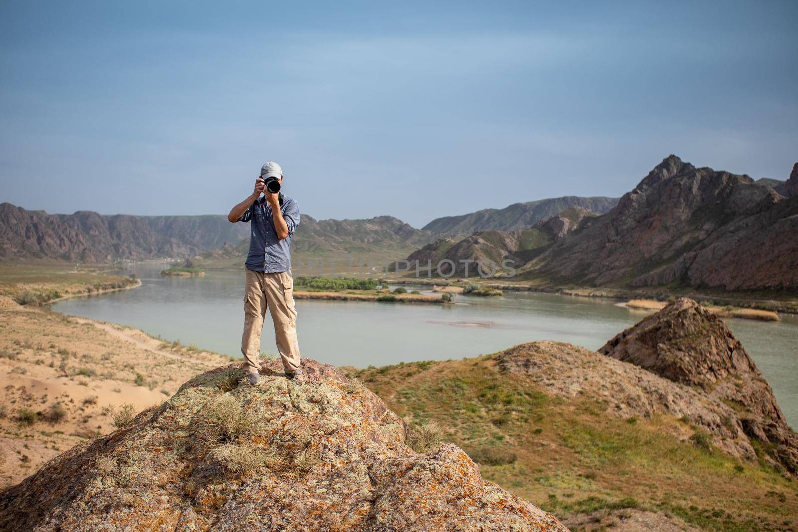 Photographer shoots a landscape from the top of a mountain. Cameraman look at camera with camera.