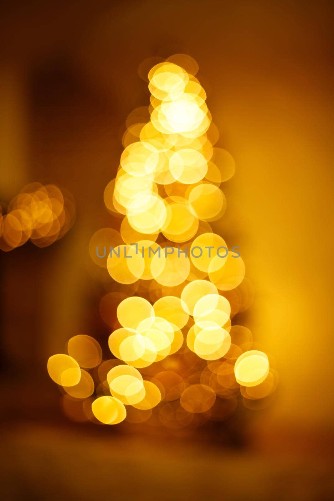 Bright golden bokeh lights in new year tree shape. Festive blurred background.