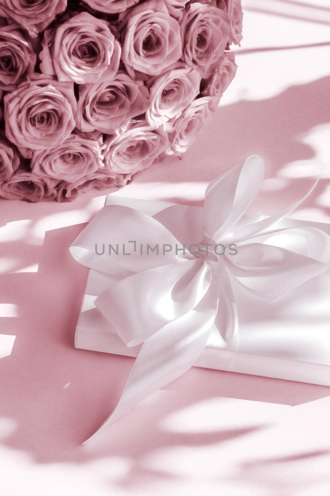 Happy holidays, luxe shopping and love gifts concept - Luxury holiday silk gift box and bouquet of roses on blush pink background, romantic surprise and flowers as birthday or Valentines Day present