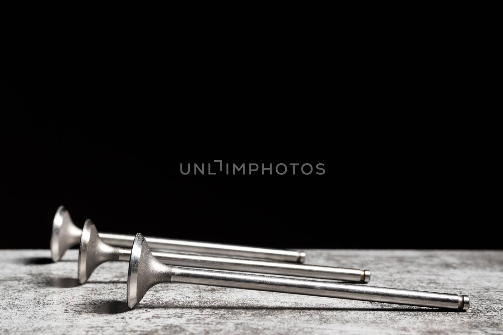 Car engine valves lie on the table on black background. Part of an internal combustion engine. copy space.