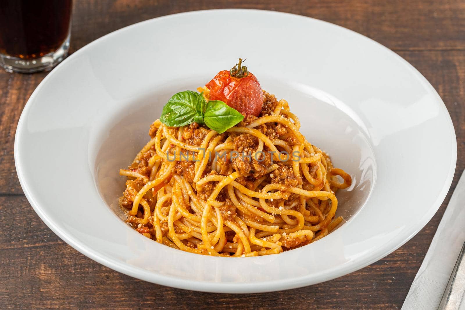 Spaghetti with bolognese sauce on white porcelain plate on wooden table by Sonat