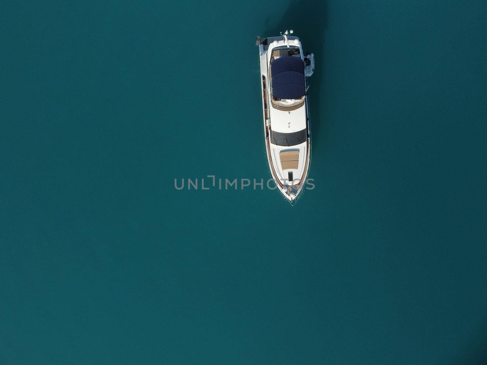 Aerial boat race. Luxury cruise trip. View from above of white boat on deep blue water. Aerial view of rich yacht sailing sea. Motor boat racing wave. Summer journey on luxury ship