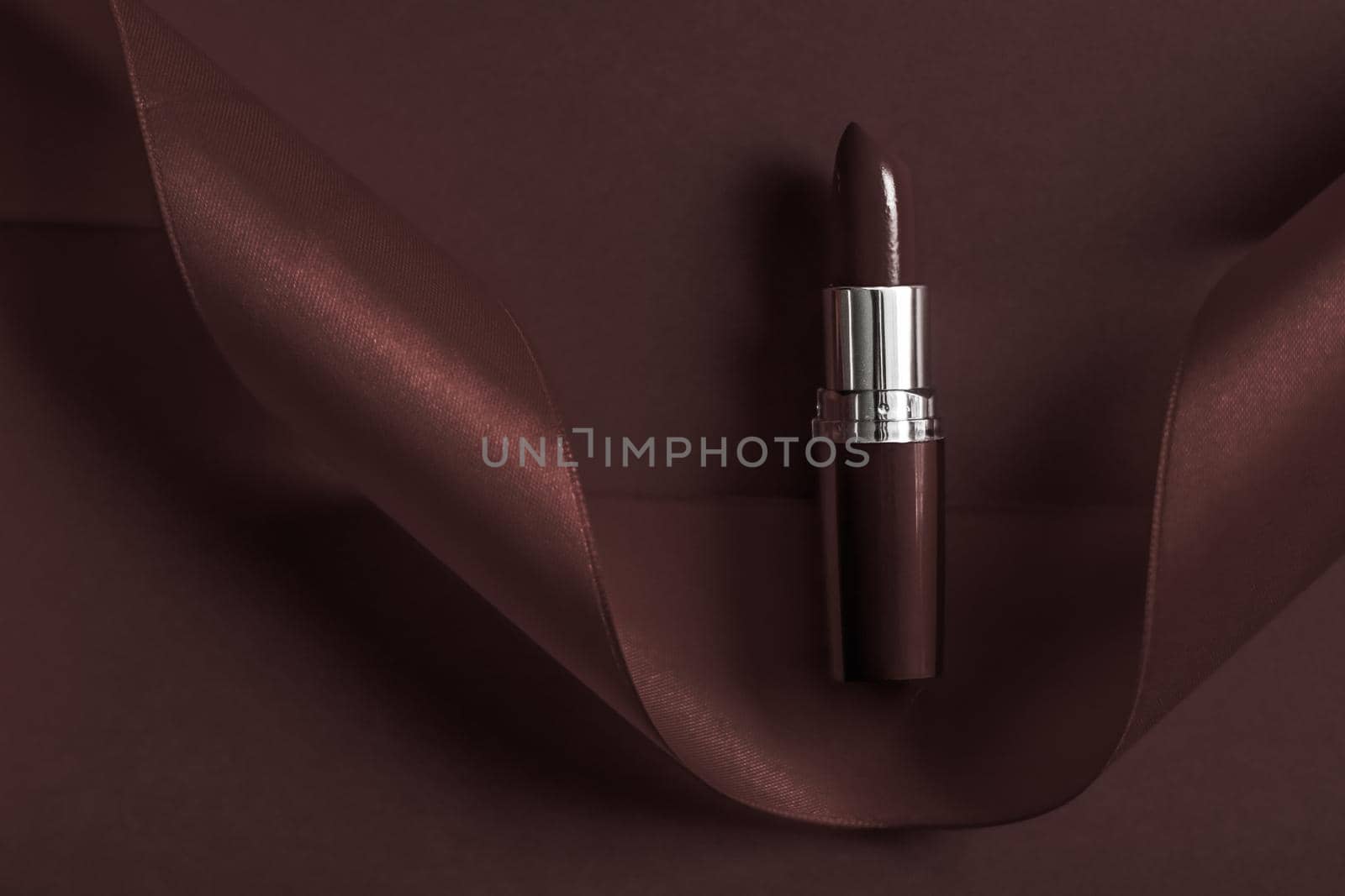 Cosmetic branding, glamour lip gloss and shopping sale concept - Luxury lipstick and silk ribbon on chocolate holiday background, make-up and cosmetics flatlay for beauty brand product design