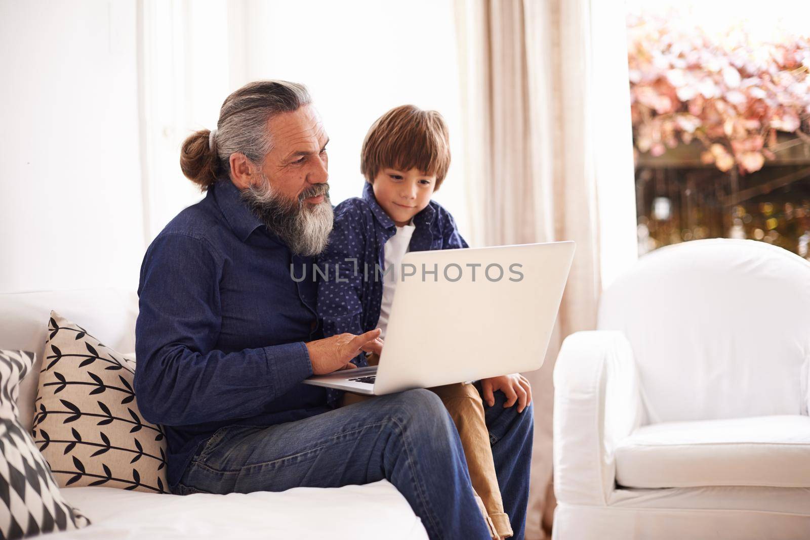 Sharing the world of technology with his grandson. a grandfather and grandson using a laptop together. by YuriArcurs