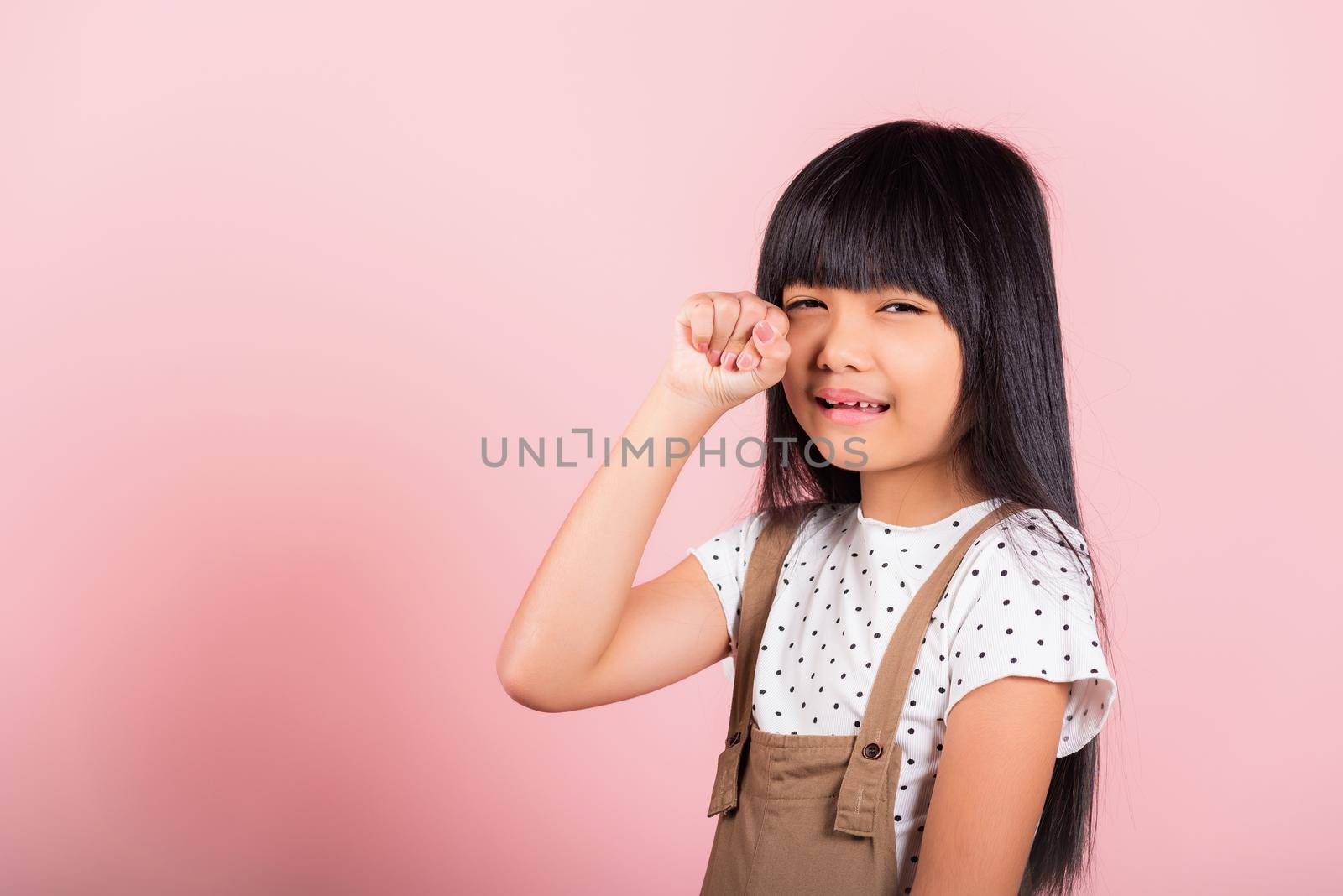 Unhappy children. Asian little kid 10 years old bad mood her cry wipe tears with fingers at studio shot isolated on pink background, child girl stress feeling sad unhappy crying