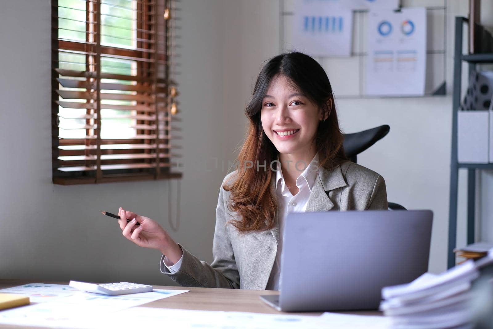 Portrait of an Asian young business Female working on a laptop computer in her workstation.Business people employee freelance online report marketing e-commerce telemarketing concept. by wichayada