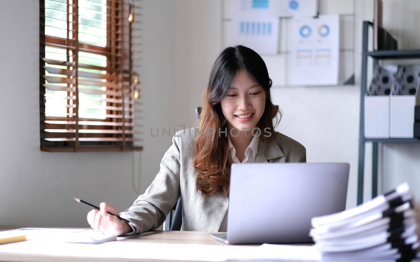 Beautiful young smiling Asian businesswoman working on laptop. Asia businesswoman working document finance and calculator in her office