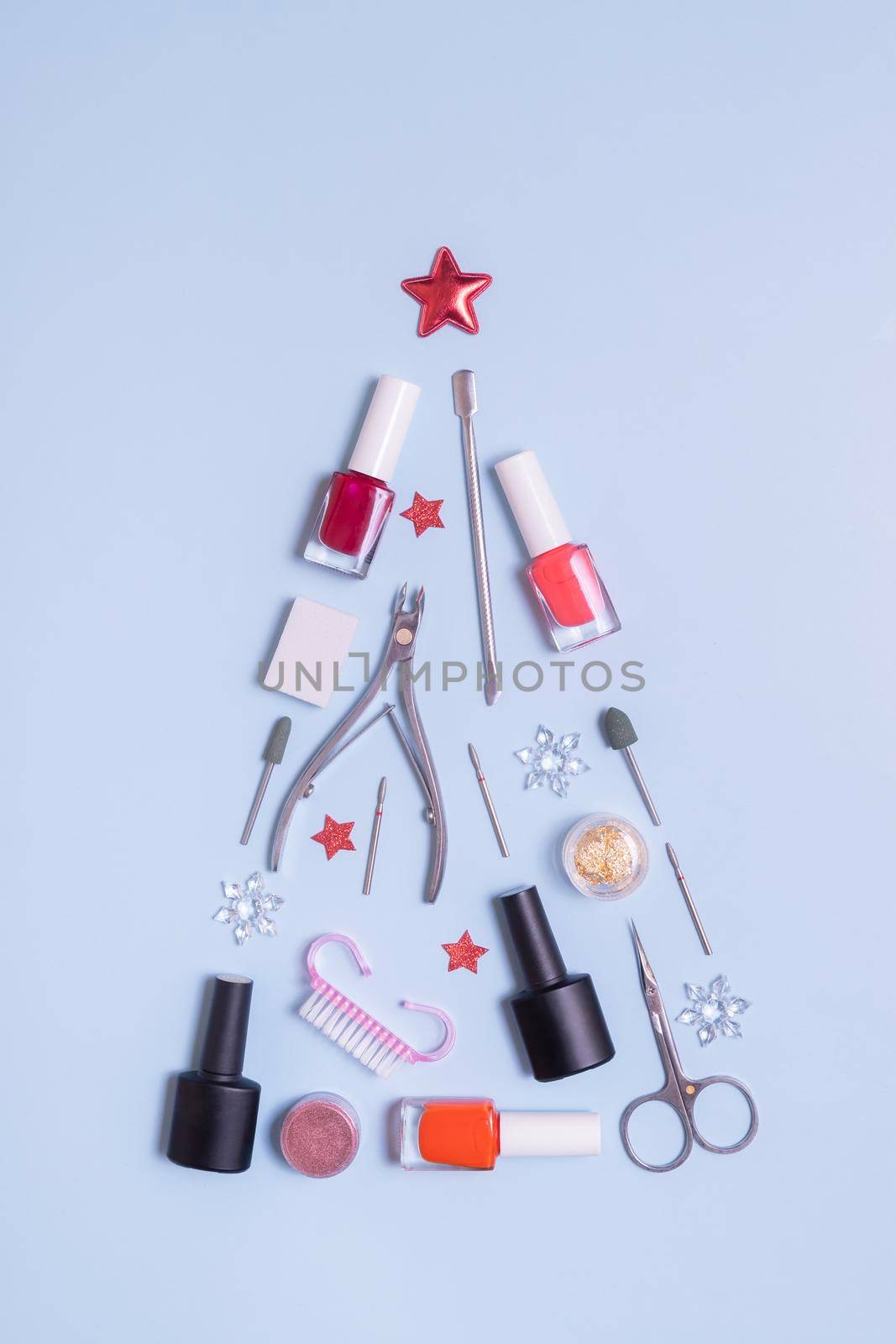 Manicure tools and nail polishes are laid out in the shape of a Christmas tree top view.