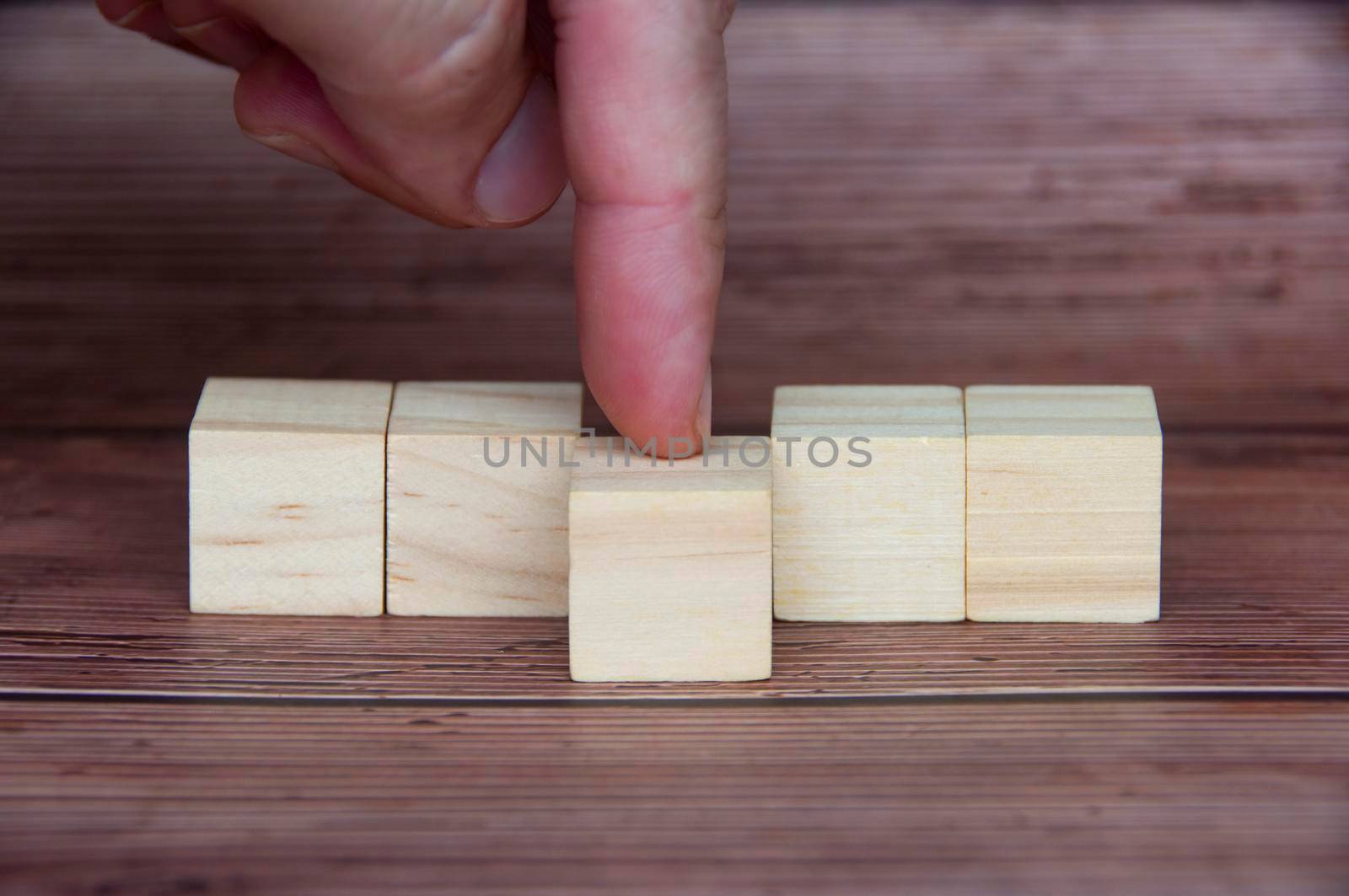 Finger pointing a wooden block with customizable space for text or ideas. Copy space.