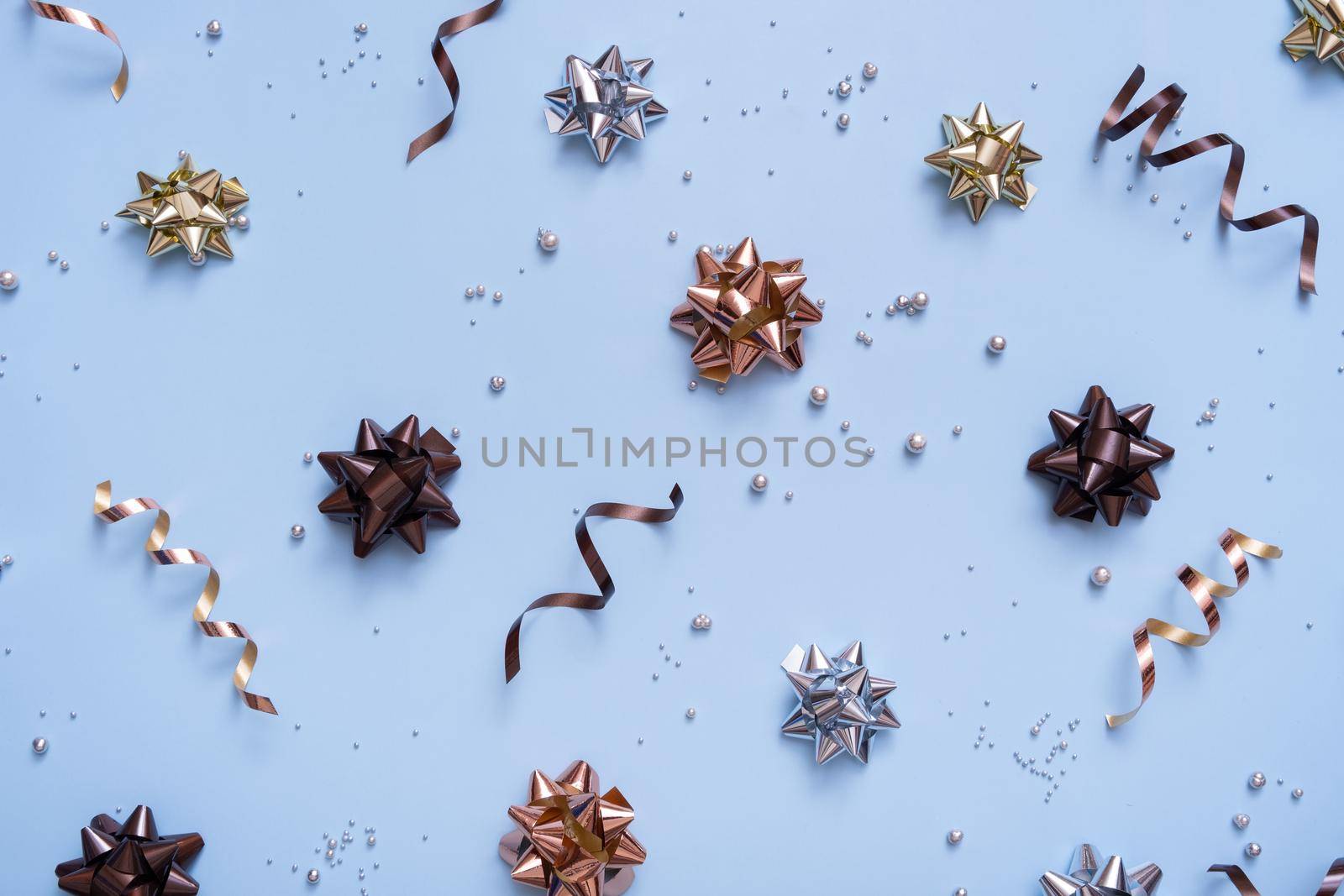Abstract festive background with bows and beads top view. New Year Christmas blue background flat lay