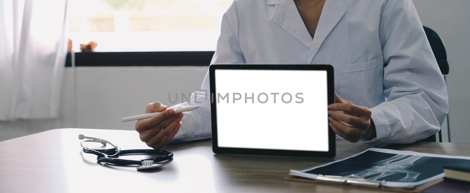 Portrait of experienced doctor woman cardiologist present modern technology white screen tablet she use consult patients wear white coat uniform stethoscope in examination room..