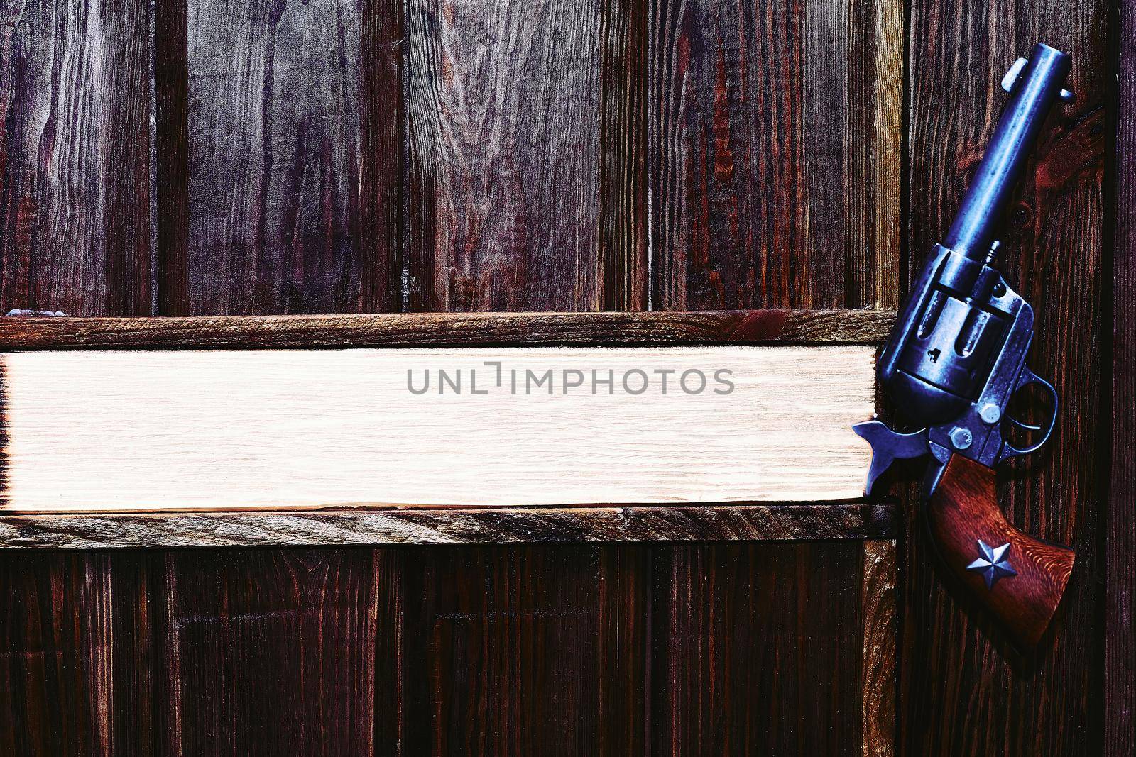 a pistol with revolving chambers enabling several shots to be fired without reloading. Cowboy gun revolver on a dark brown wooden wall . Space for text. Boss's office