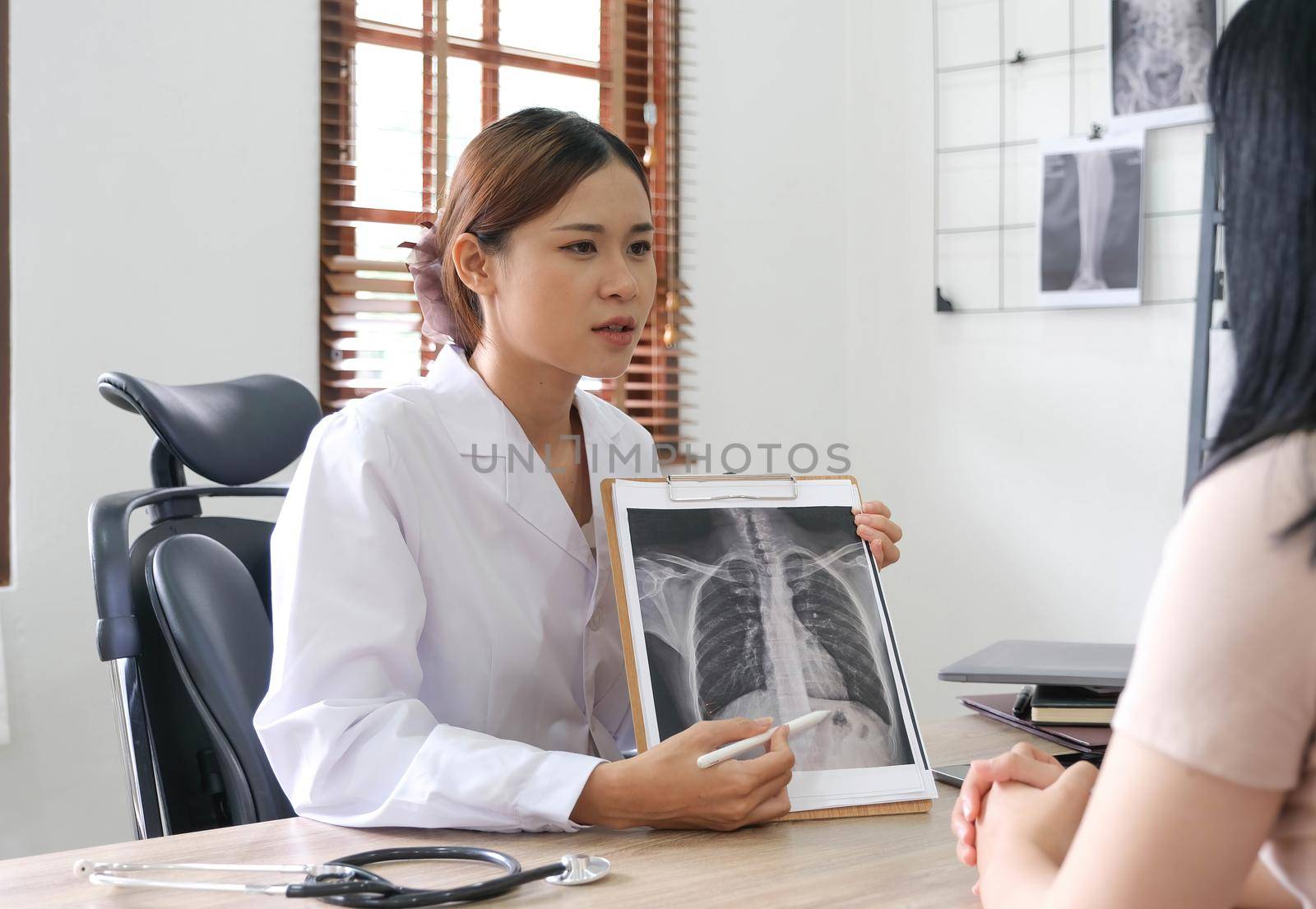 Doctor showing x-ray result to patient in clinic. by wichayada