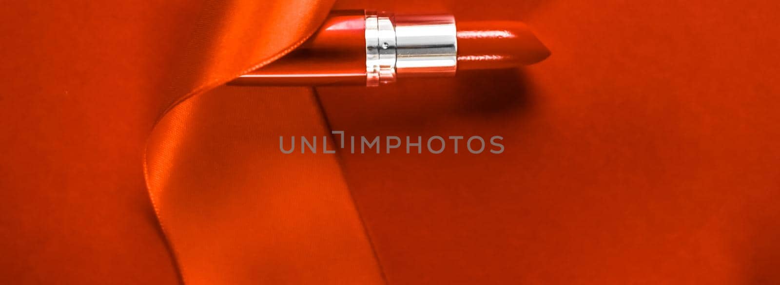 Cosmetic branding, glamour lip gloss and shopping sale concept - Luxury lipstick and silk ribbon on orange holiday background, make-up and cosmetics flatlay for beauty brand product design