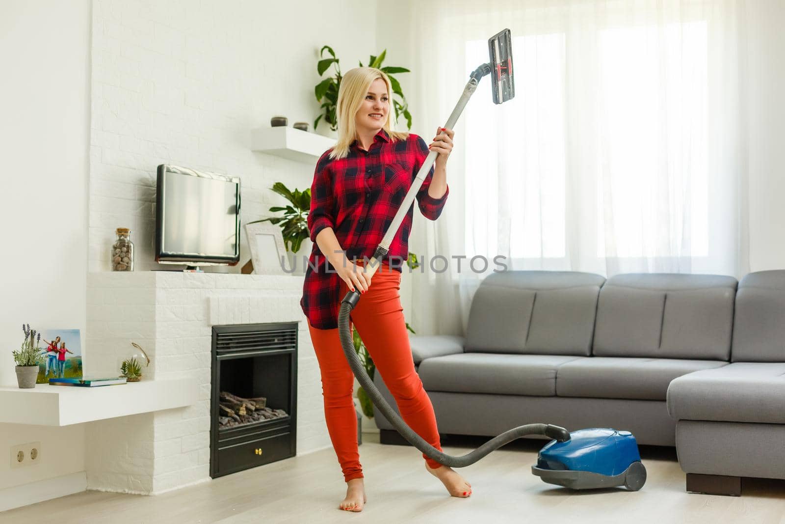 Happy woman cleaning home, dancing with vacuum cleaner and having fun, copy space. Housework, chores concept
