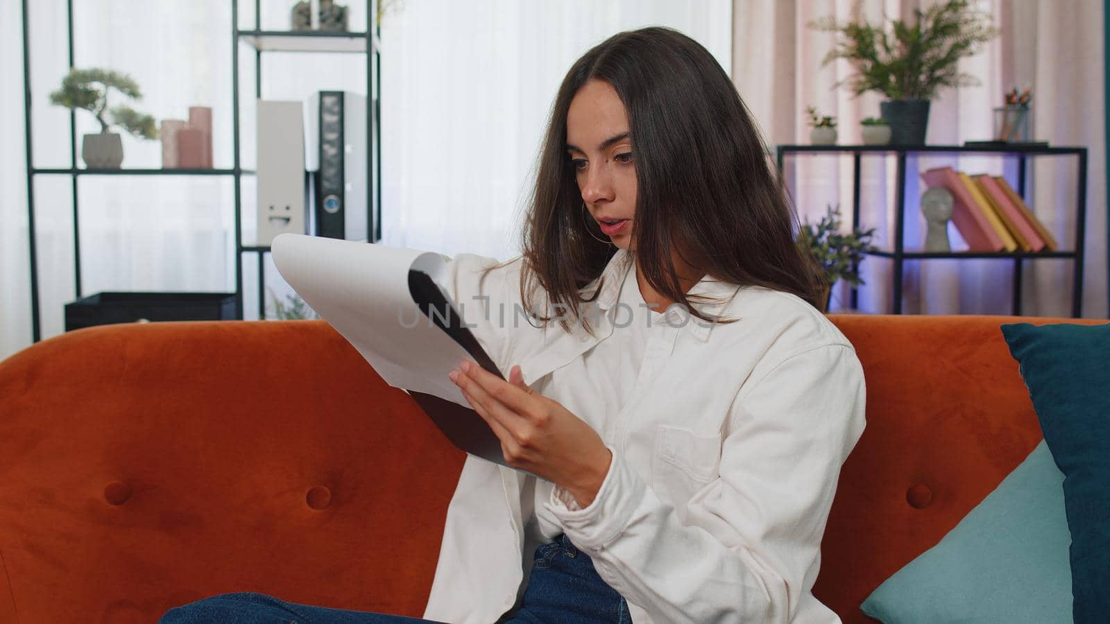 Girl reading paper documents, working at home. Freelance businesswoman reviewing reports. Young woman calculate costs, incomes, expenses, estimate budget for project, accountant financial inspection